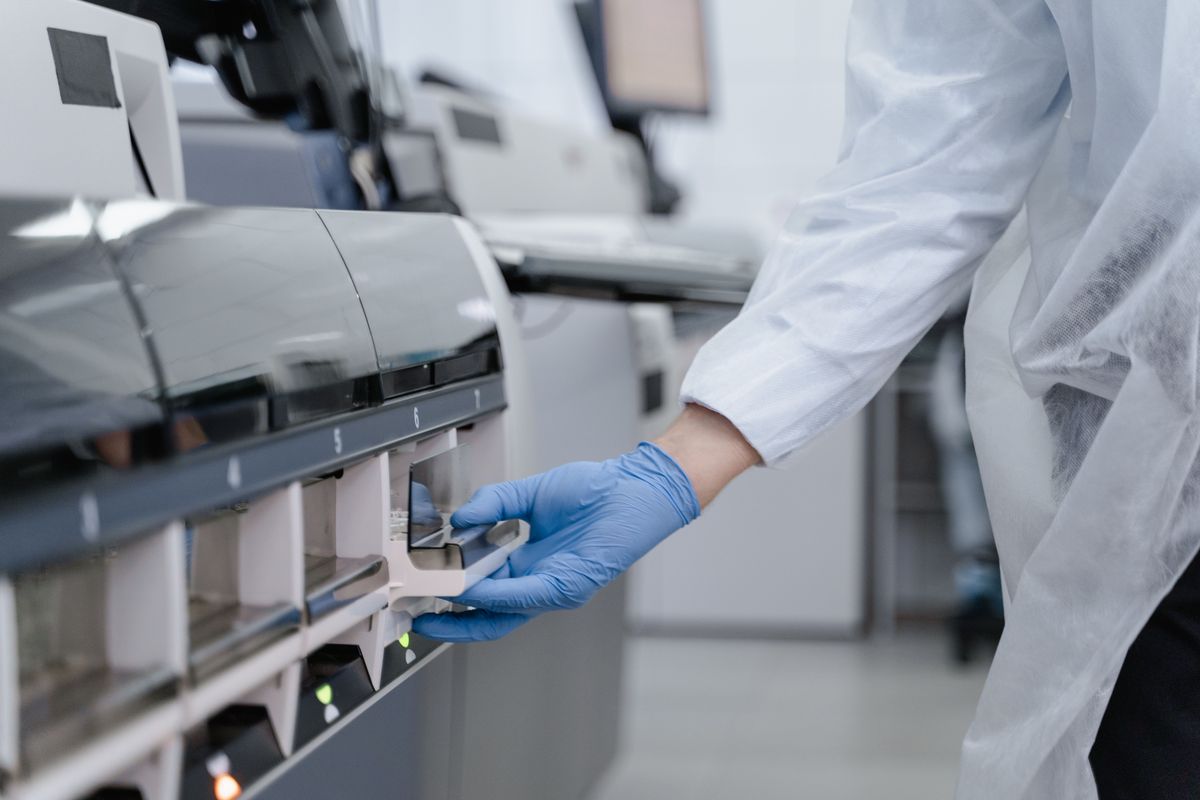 Gloved hands operating controlled laboratory equipment with numbered sample positions.